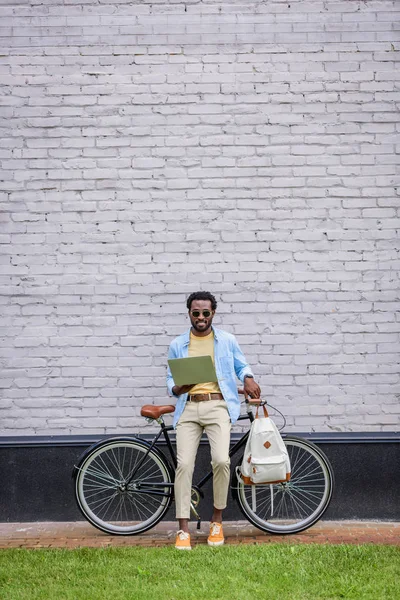 Stylowy African American Man Stoi Ścianie Cegły Pobliżu Roweru Pomocą — Zdjęcie stockowe