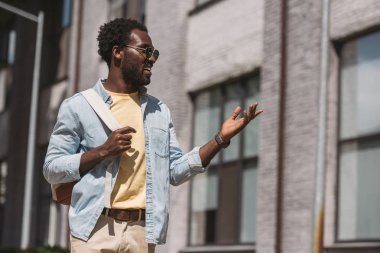 neşeli, şık afro-amerikan adam uzağa bakarken gesturing
