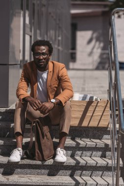 üzgün afro-amerikan işadamı kapalı gözlerle merdivenlerde oturan