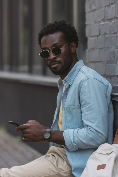 Snygg Afrikansk Amerikansk Man Solglasögon Med Smartphone Och Titta Kamera — Stockfoto