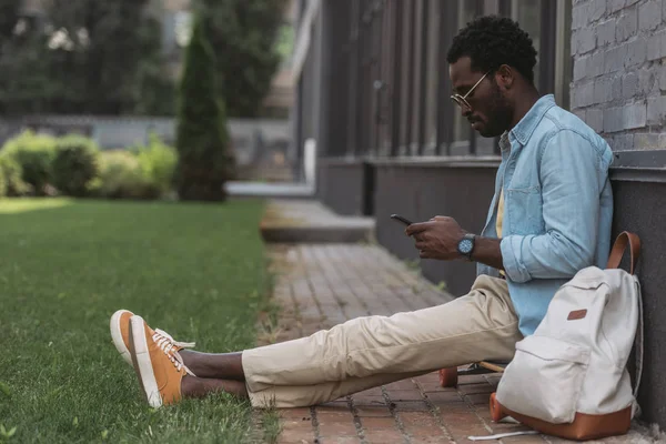 Snygg Afrikansk Amerikansk Man Sitter Longboard Och Använda Smartphone — Stockfoto