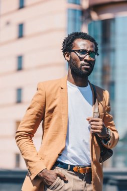 emin afrikalı amerikalı işadamı cebinde el ele tutarak ve uzağa bakıyor