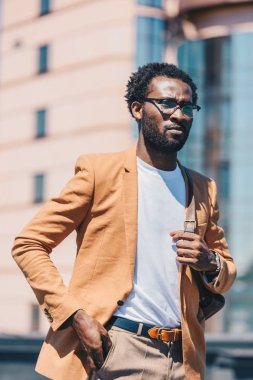 ciddi afro-amerikan işadamı cebinde el tutarak ve uzağa bakıyor