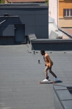 güneşli çatı üzerinde longboard sürme şık afrikalı Amerikalı işadamı