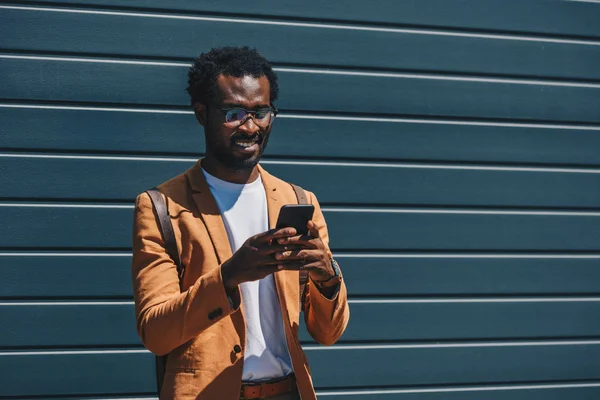 Smiling African American Businessman Using Smartphone While Standing Wall — Stock Photo, Image