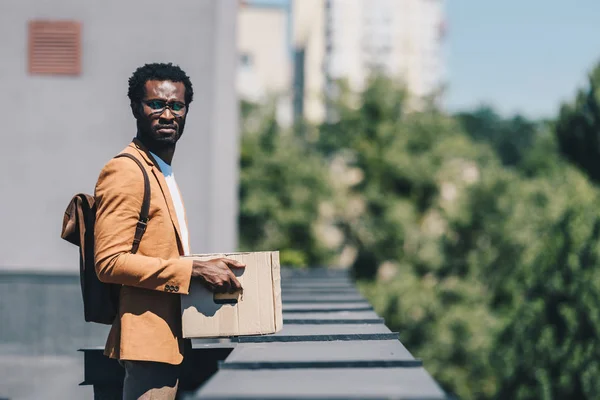 Pensativo Empresário Afro Americano Segurando Caixa Papelão Olhando Para Longe — Fotografia de Stock