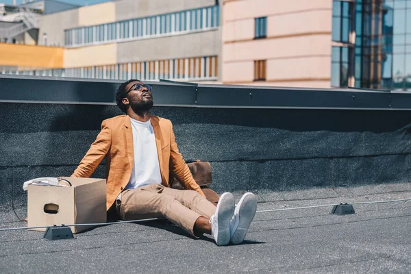 Depressed Fired African American Businessman Looking While Sitting Rooftop Carton — Stock Photo, Image