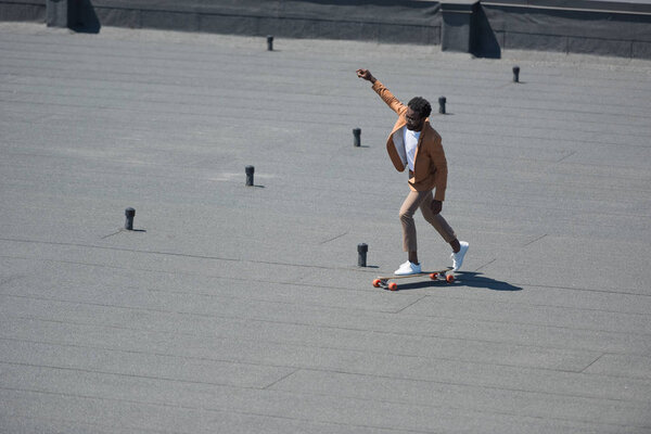 стильный африканский американский бизнесмен, катающийся на лонборде на солнечной крыше
