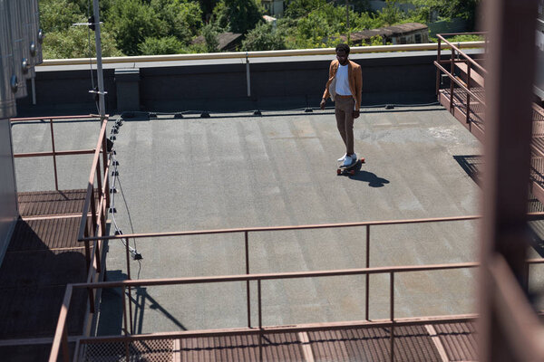 селективный фокус африканского американского бизнесмена, катающегося на длинной доске на солнечной крыше
