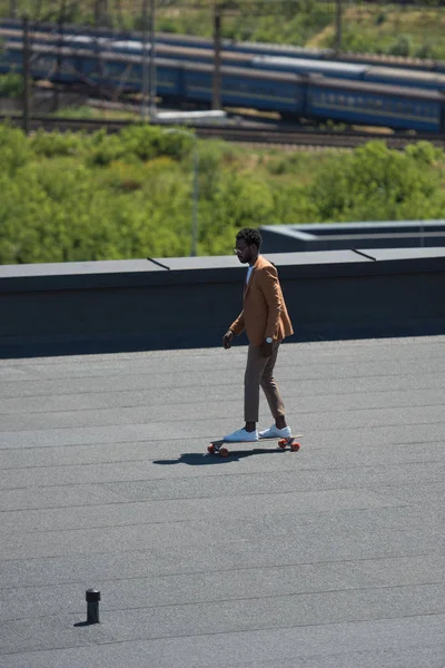 Hombre Negocios Afroamericano Montando Longboard Azotea Soleada Con Ferrocarriles Trenes —  Fotos de Stock