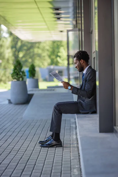 Przystojny African American Biznesmen Czytanie Gazety Siedząc Pobliżu Biurowego Budynku — Zdjęcie stockowe