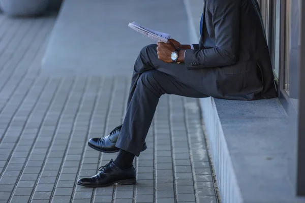 Przycięte Widzenia African American Biznesmen Czytania Gazety Siedząc Parapet — Zdjęcie stockowe