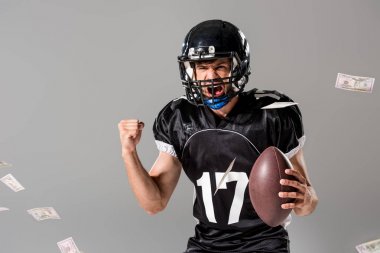 top ile Amerikan futbol oyuncusu bağırarak Izole gri üzerinde düşen para ile