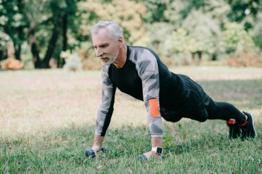 yakışıklı olgun sporcu parkta çim üzerinde barbells ile push up yapıyor