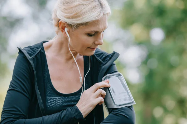 Ελκυστική Ώριμη Αθλητική Γυναίκα Χρησιμοποιώντας Smartphone Θήκη Περιβραχιόνιο Ακούγοντας Μουσική — Φωτογραφία Αρχείου