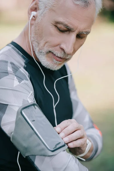 Stilig Mogen Sportsman Använda Smartphone Armband Fall Och Lyssna Musik — Stockfoto