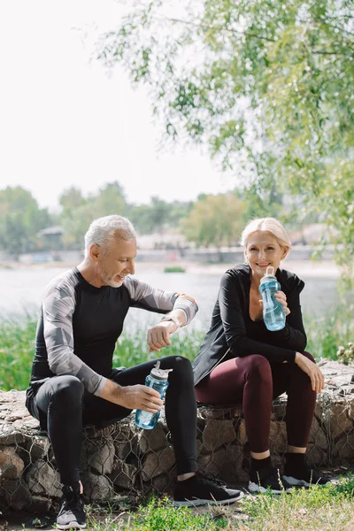 Smiling Sportsman Sportswoman Holding Sports Bottles While Sitting Pavement Park — Stock Photo, Image