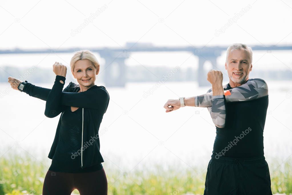 mature sportsman and sportswoman looking at camera while warming up in park