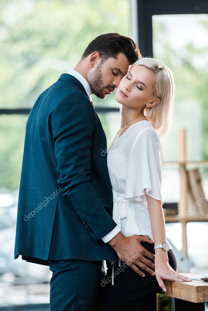 handsome bearded man touching attractive woman with closed eyes 