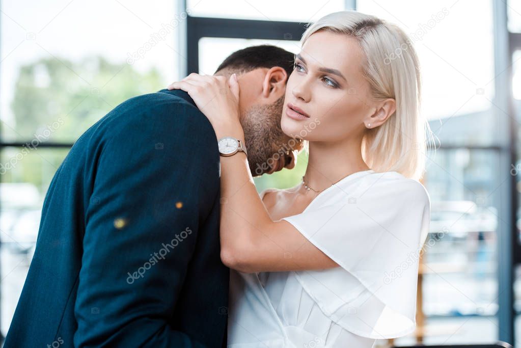 beautiful blonde woman hugging with bearded businessman in office 
