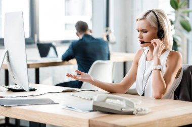 Ofis konuşurken kulaklıkta üzgün sarışın kadın seçici odak 
