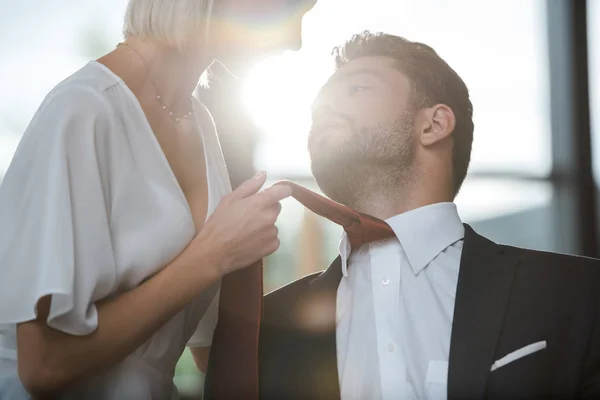 オフィスでいちゃついている間 ハンサムな男のネクタイに触れる情熱的な女性のトリミングされたビュー — ストック写真