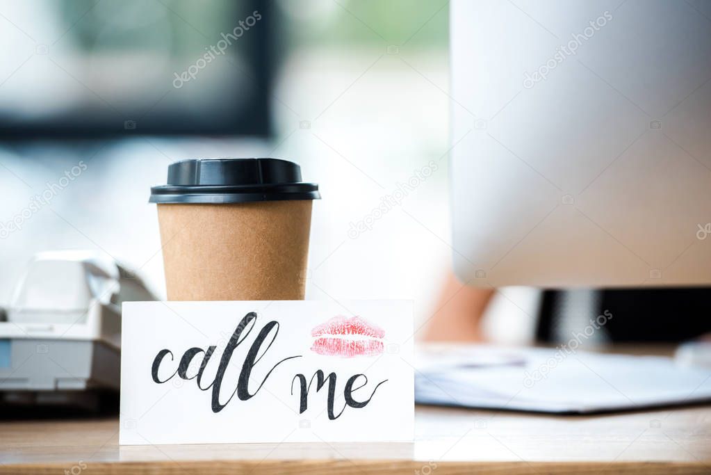 card with call me lettering near paper cup in office 