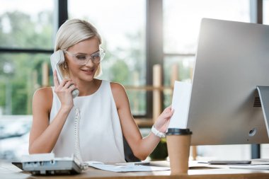 Kağıt fincan yakın Retro telefon konuşurken çekici sarışın işkadını gülümseyen seçici odak