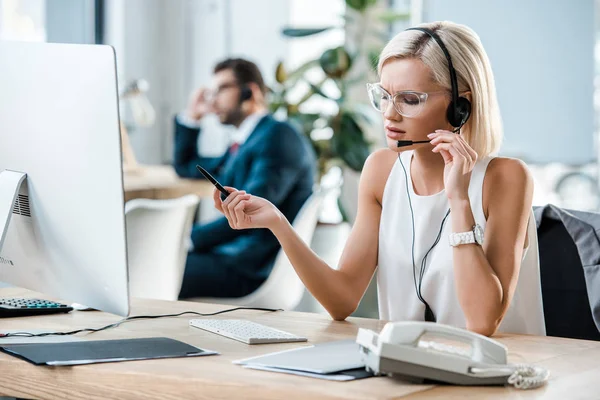 Enfoque Selectivo Del Operador Rubio Auriculares Celebración Pluma Mientras Habla — Foto de Stock