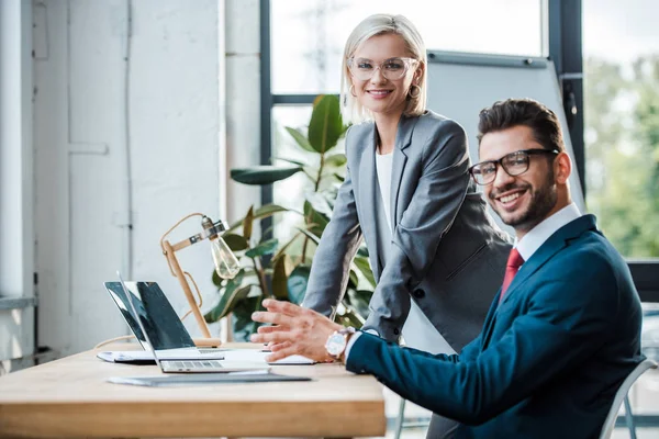 Glada Medarbetare Glasögon Tittar Kameran Nära Bärbara Datorer Office — Stockfoto