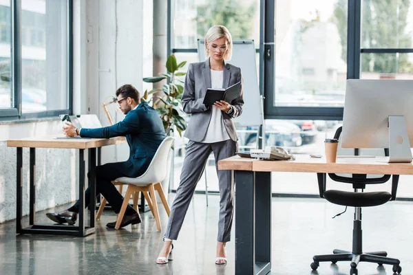 Atractivo Hombre Negocios Gafas Mirando Cuaderno Mientras Está Pie Oficina — Foto de Stock