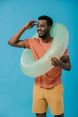 mavi izole yüzme halkası ile ayakta iken neşeli afrikalı amerikalı adam gesturing 