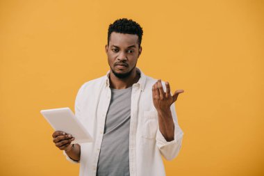 turuncu izole dijital tablet tutarken afro-amerikan adam gesturing üzgün