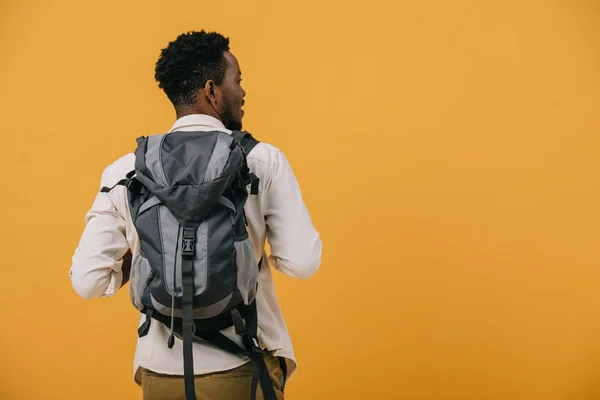 オレンジ色に隔離されたバックパックで立っているアフリカ系アメリカ人の男性 — ストック写真