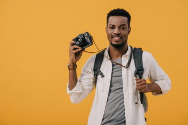 happy african american man holding digital camera isolated on orange clipart