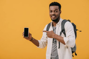 turuncu izole boş ekran ile akıllı telefon parmak ile işaret neşeli afrikalı amerikalı adam 