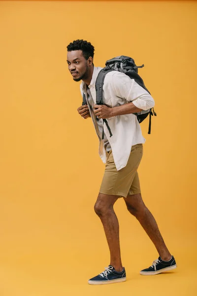 オレンジの上にバックパックを持って歩くカーリー幸せなアフリカ系アメリカ人の男性 — ストック写真