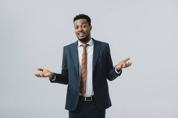 happy african american man showing shrug gesture isolated on grey 