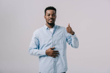 neşeli afrikalı amerikalı adam başparmak gösteren ve gri izole mide dokunmadan 