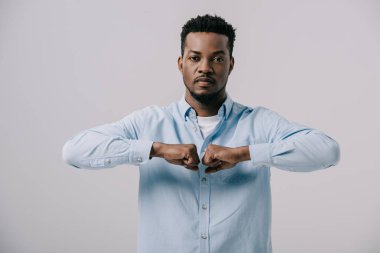 gri izole sıkıştırılmış yumruklar ile ayakta yakışıklı afro-amerikan adam 