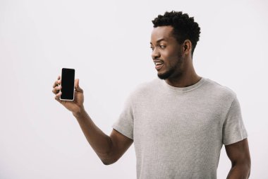 beyaz izole boş ekran ile akıllı telefon bakarak mutlu afrikalı amerikalı adam 