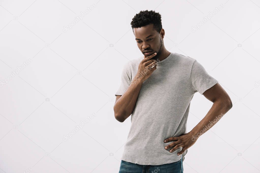 pensive african american man standing with hand on hip and touching face isolated on white 