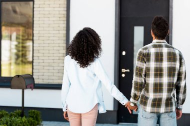 afrikalı Amerikalı karı koca el ele tutuşarak ve eve bakarak geri görünümü 