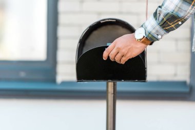 cropped view of man opening black mailbox with hand clipart