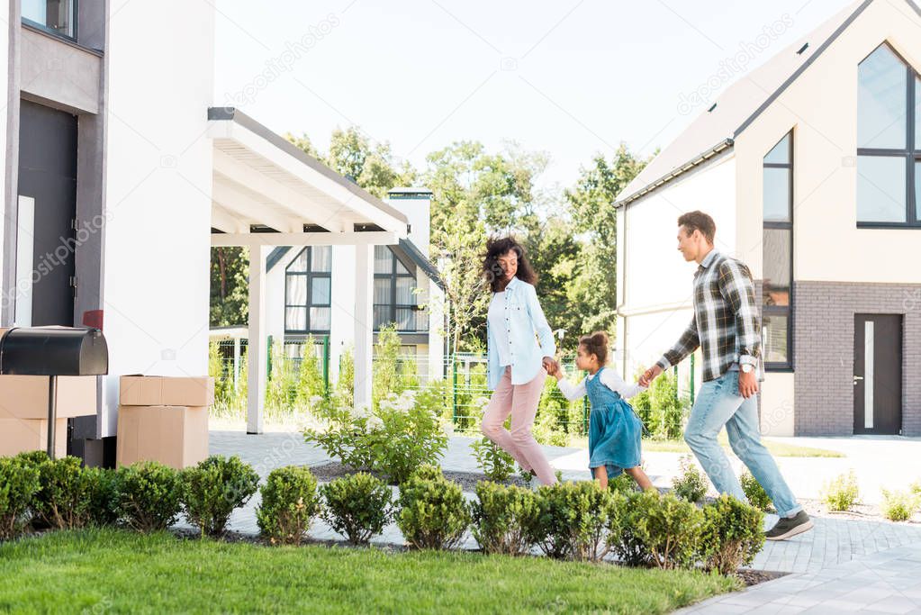 full length view of happy african american family running to new house while mother looking at kid 