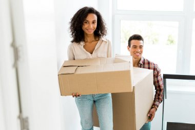 selective focus of african american woman and man going upstairs with boxes clipart