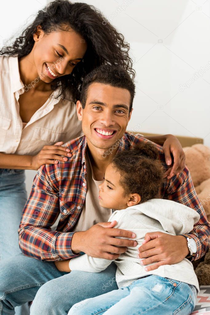 african american man hugging daughter while woman standing near husband 