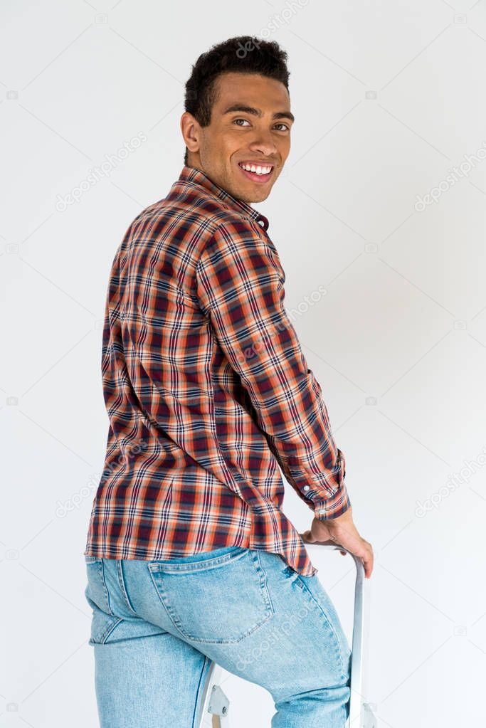 handsome african american man standing at ladder and looking at camera 