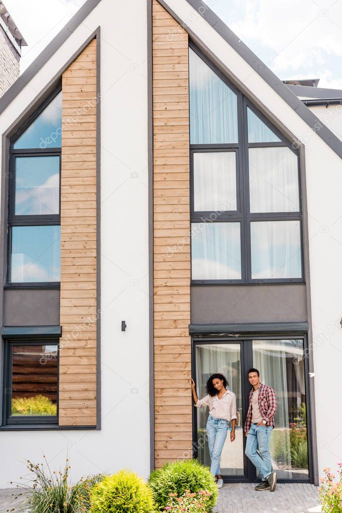 full length view of big new house and african american couple standing near building 