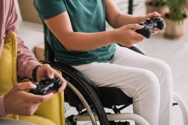 Kiev, Ukrayna - 10 Temmuz 2019: Evde erkek arkadaşı ile video oyunu oynayan genç engelli kadının kırpılmış görünümü.